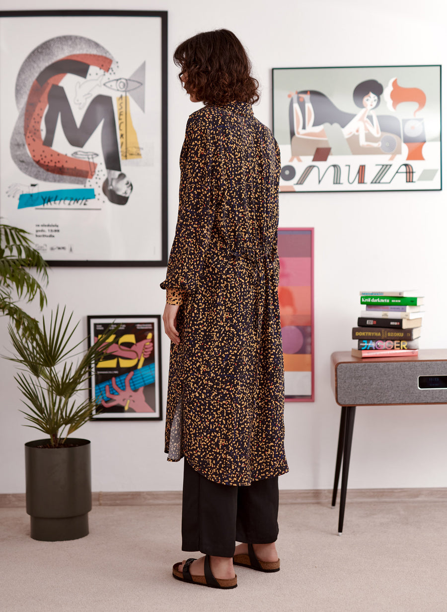 Yellow balck spaltter print shirt dress with contrast cuffs worn by a model. Back. Styled with wide trouser and sandals.
